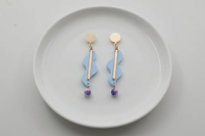 Blue Esme long acrylic statement earrings arranged on a white plate