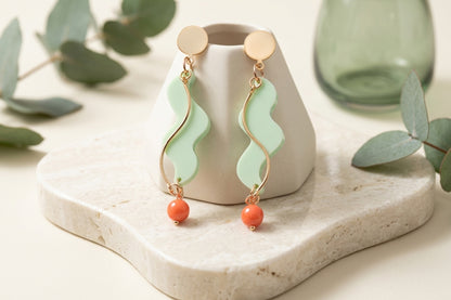 Green Esme long acrylic statement earrings in a styled product setting