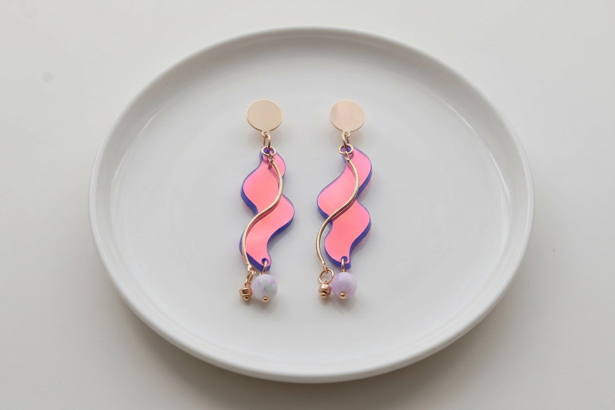 HB Esme long acrylic statement earrings arranged on a white plate