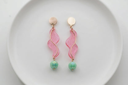 Pink Esme long acrylic statement earrings arranged on a white plate