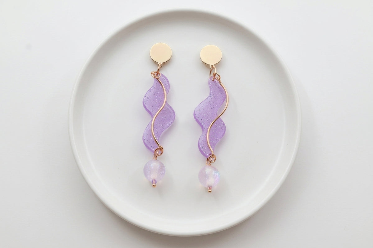 Purple Esme long acrylic statement earrings arranged on a white plate
