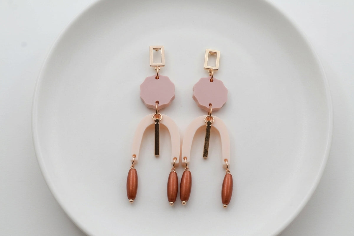 Beige Eva geometric beaded drop earrings arranged on a white plate