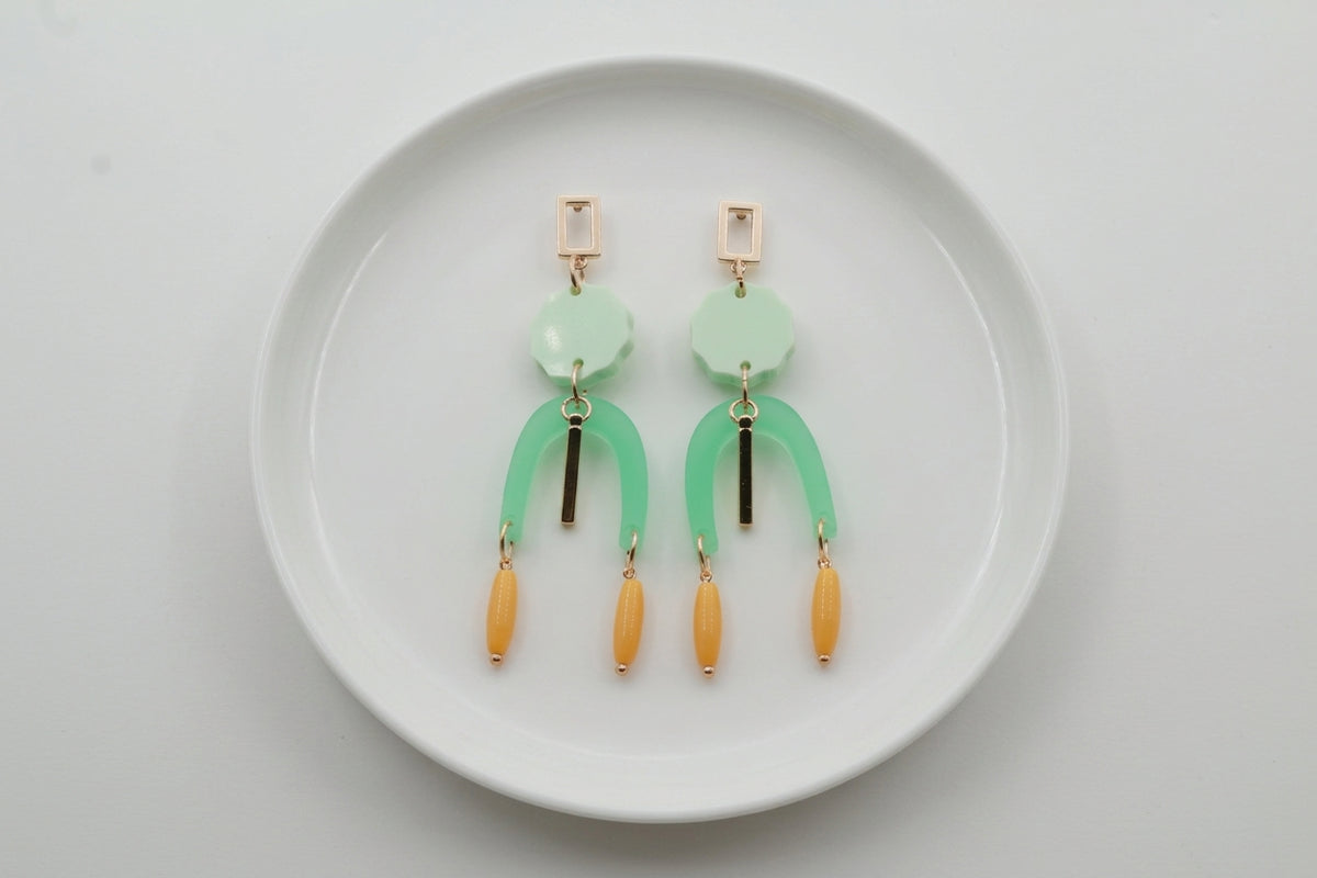 Green Eva geometric beaded drop earrings arranged on a white plate