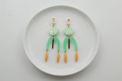Green Eva geometric beaded drop earrings arranged on a white plate