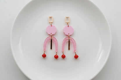 Pink Eva geometric beaded drop earrings arranged on a white plate
