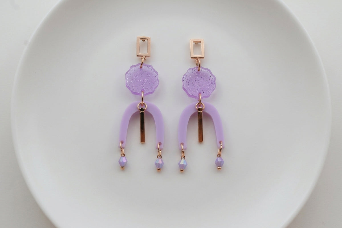Purple Eva geometric beaded drop earrings arranged on a white plate