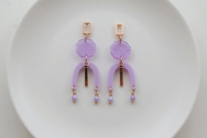 Purple Eva geometric beaded drop earrings arranged on a white plate