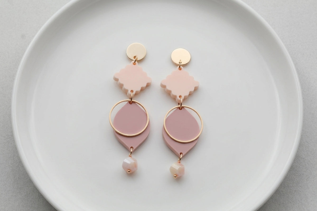 Beige Fien long geometric drop earrings arranged on a white plate