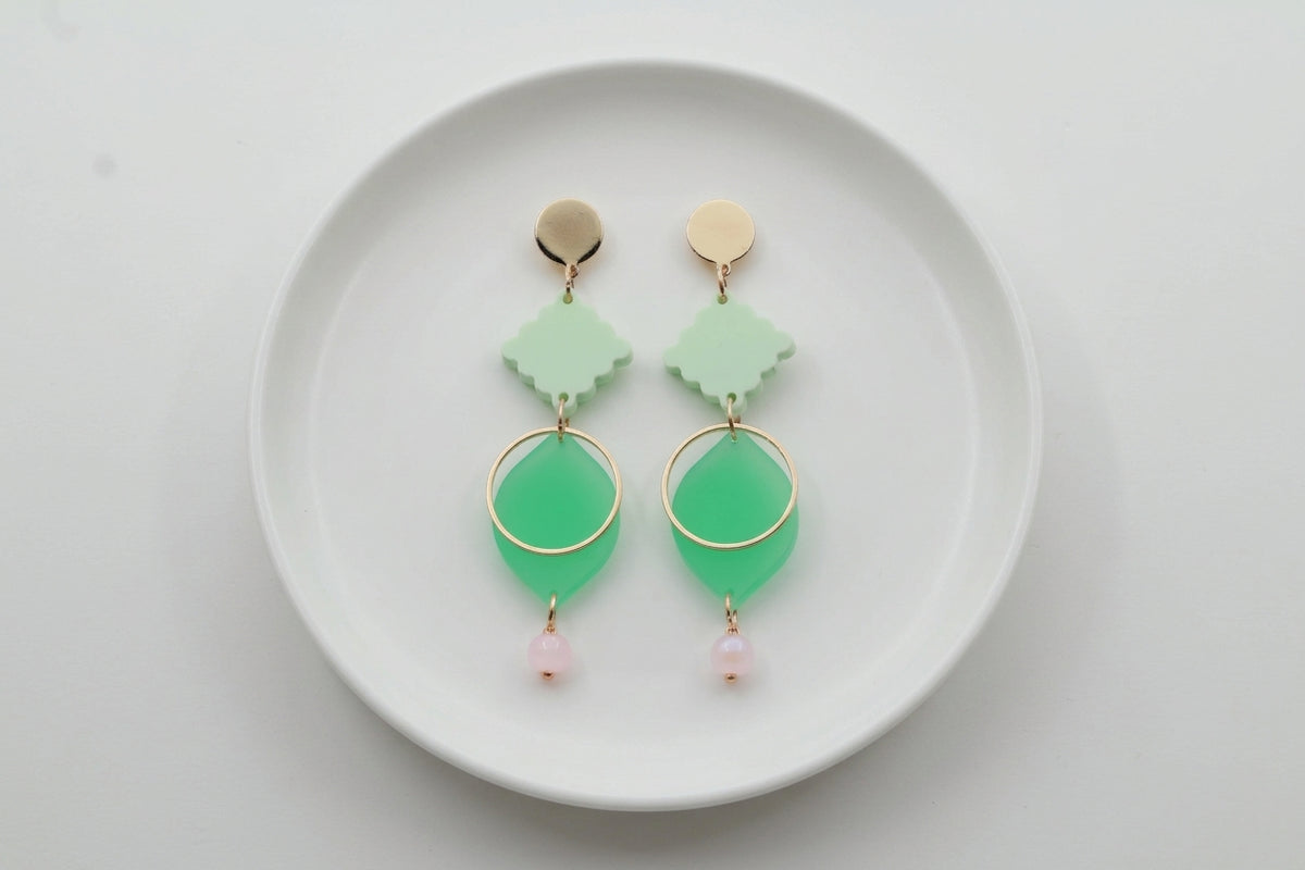 Green Fien long geometric drop earrings arranged on a white plate