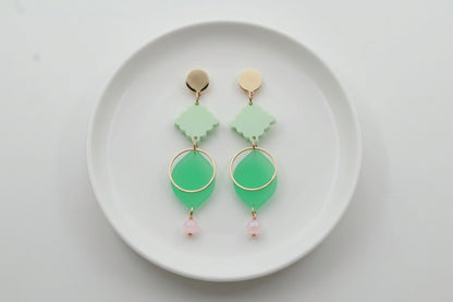 Green Fien long geometric drop earrings arranged on a white plate