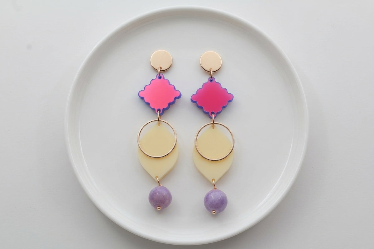 HB Fien long geometric drop earrings arranged on a white plate
