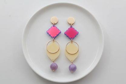 HB Fien long geometric drop earrings arranged on a white plate