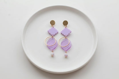 Purple Fien long geometric drop earrings arranged on a white plate