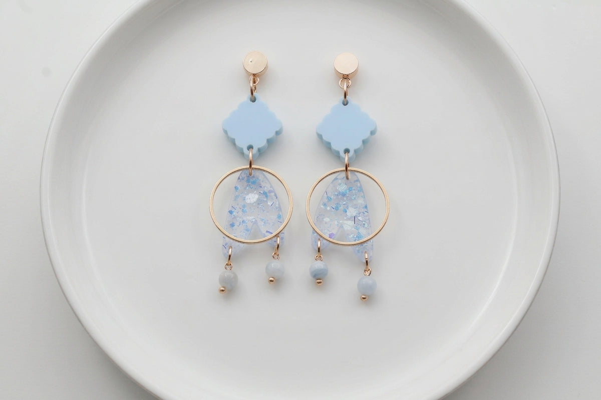Blue Fleur geometric acrylic statement earrings arranged on a white plate