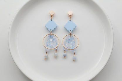 Blue Fleur geometric acrylic statement earrings arranged on a white plate