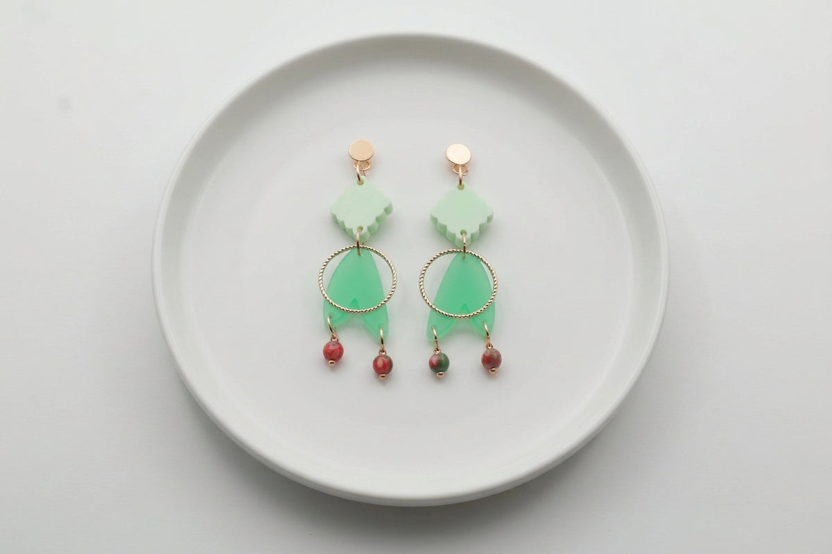 Green Fleur geometric acrylic statement earrings arranged on a white plate