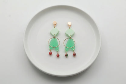 Green Fleur geometric acrylic statement earrings arranged on a white plate