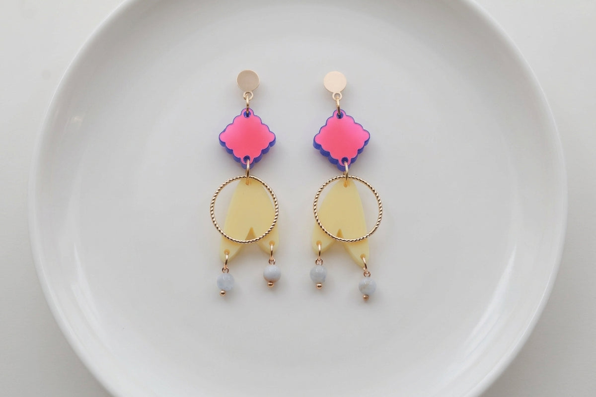 HB Fleur geometric acrylic statement earrings arranged on a white plate