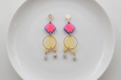 HB Fleur geometric acrylic statement earrings arranged on a white plate