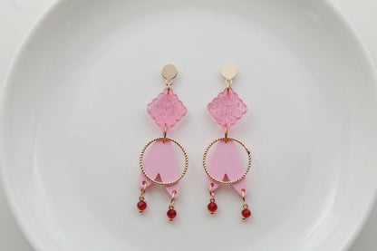Pink Fleur geometric acrylic statement earrings arranged on a white plate