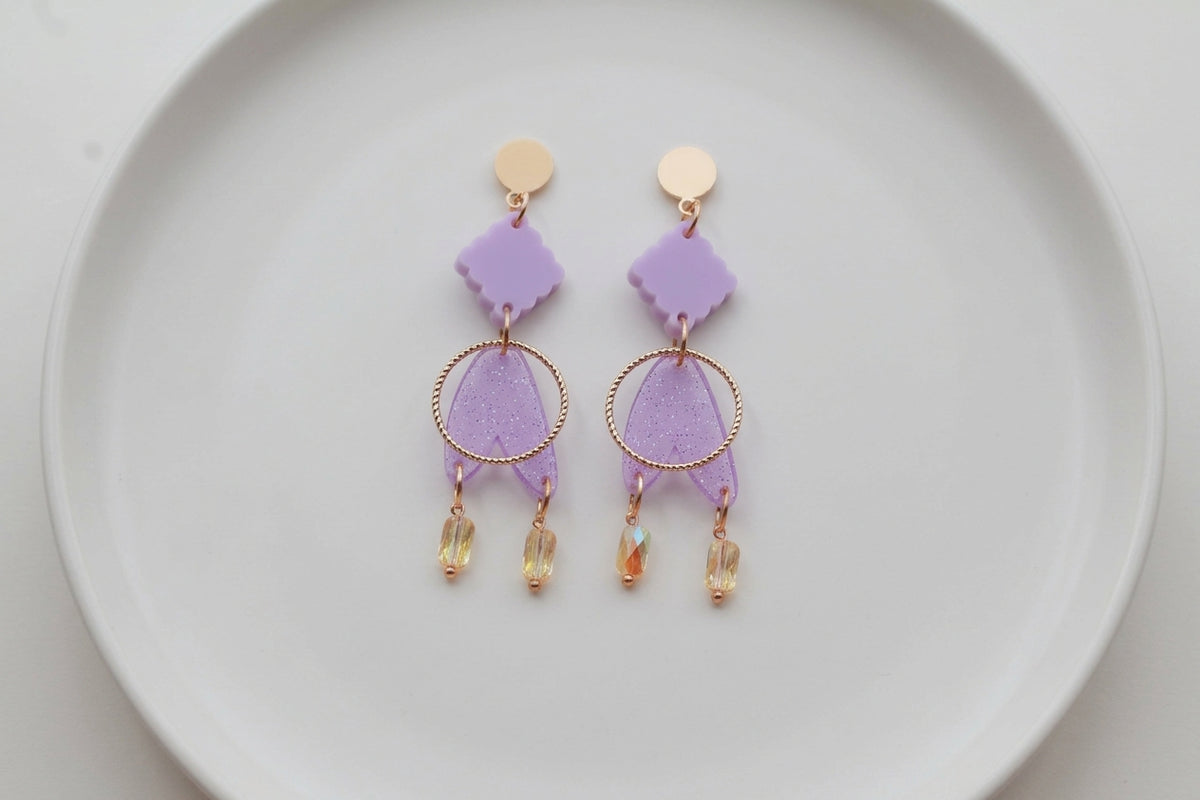 Purple Fleur geometric acrylic statement earrings arranged on a white plate