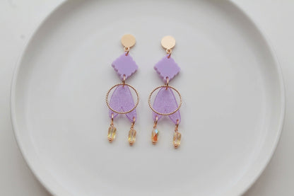Purple Fleur geometric acrylic statement earrings arranged on a white plate