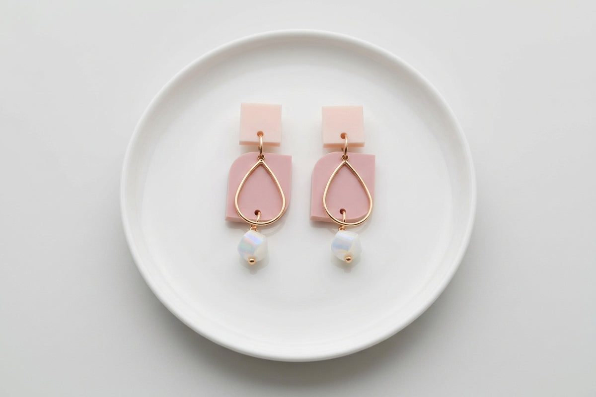 Beige Freya small geometric dangle earrings arranged on a white plate