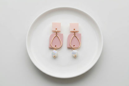 Beige Freya small geometric dangle earrings arranged on a white plate