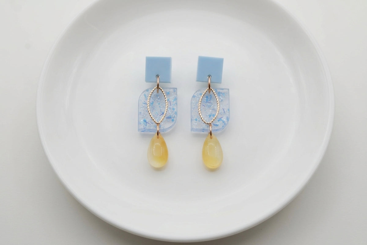 Blue Freya small geometric dangle earrings arranged on a white plate