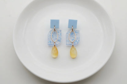 Blue Freya small geometric dangle earrings arranged on a white plate