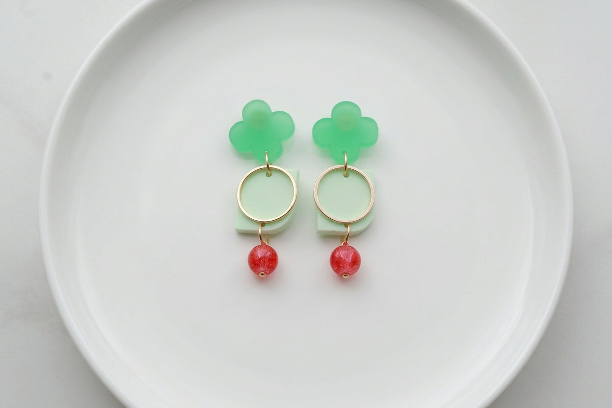 Green Freya small geometric dangle earrings arranged on a white plate