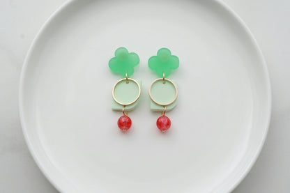 Green Freya small geometric dangle earrings arranged on a white plate