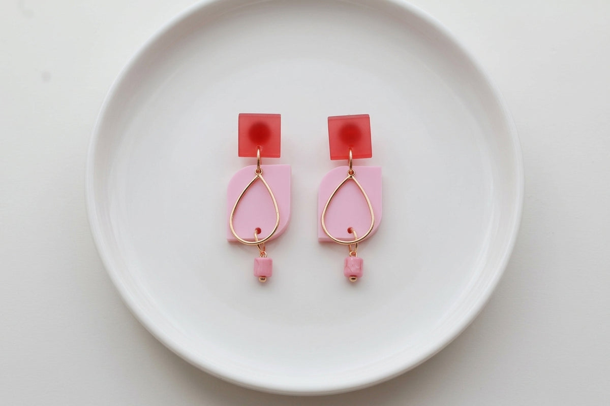 Pink Freya small geometric dangle earrings arranged on a white plate