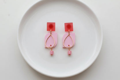Pink Freya small geometric dangle earrings arranged on a white plate