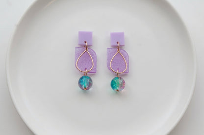 Purple Freya small geometric dangle earrings arranged on a white plate