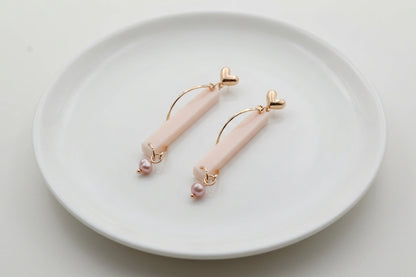 Beige Ina long rectangle acrylic earrings arranged on a white plate