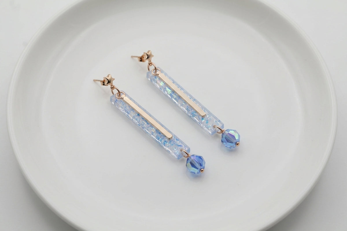 Blue Ina long rectangle acrylic earrings arranged on a white plate