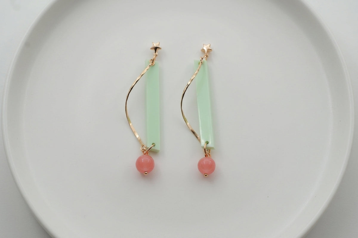 Green Ina long rectangle acrylic earrings arranged on a white plate