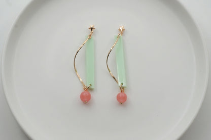 Green Ina long rectangle acrylic earrings arranged on a white plate