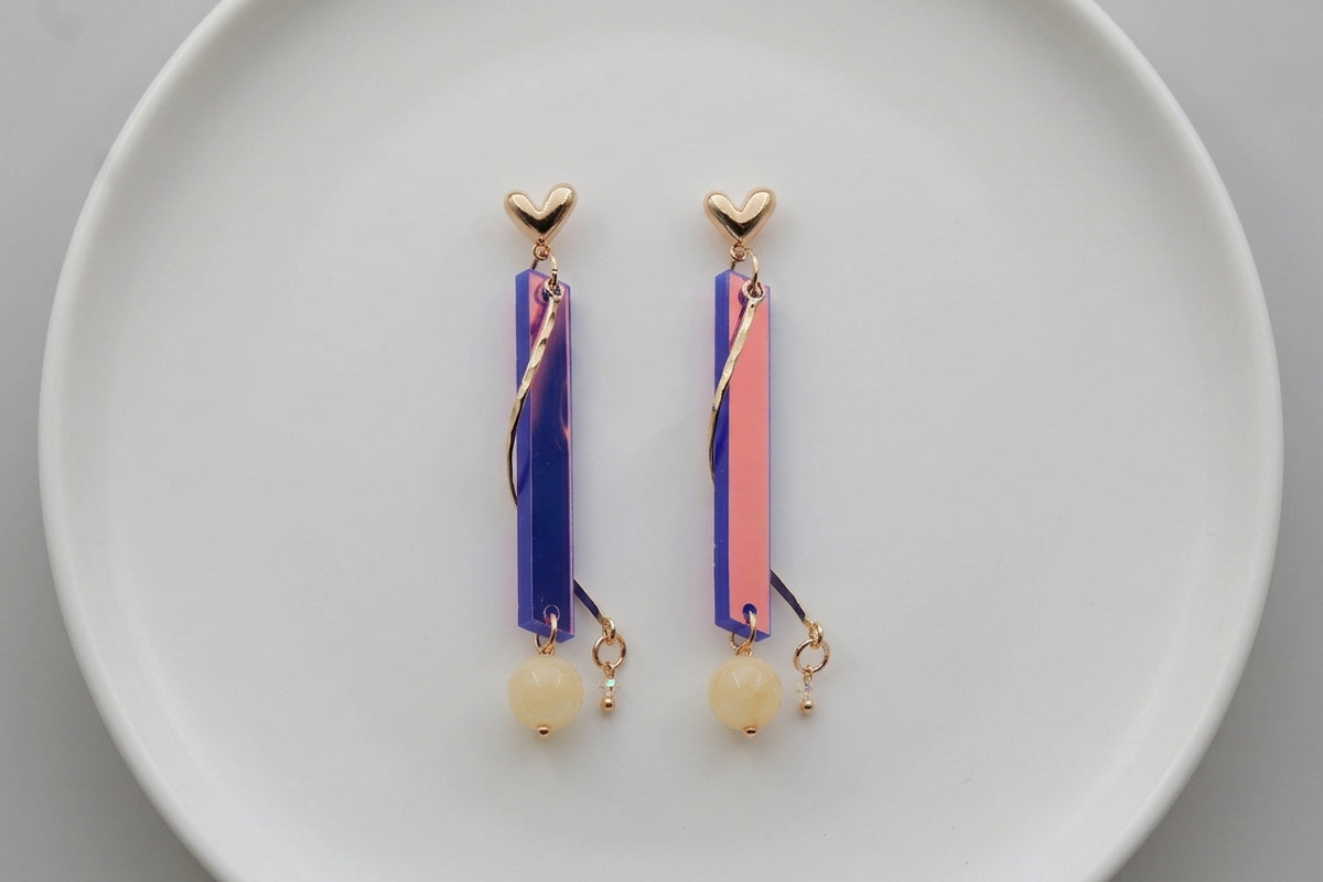 HB Ina long rectangle acrylic earrings arranged on a white plate