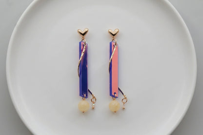 HB Ina long rectangle acrylic earrings arranged on a white plate