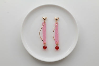 Pink Ina long rectangle acrylic earrings arranged on a white plate