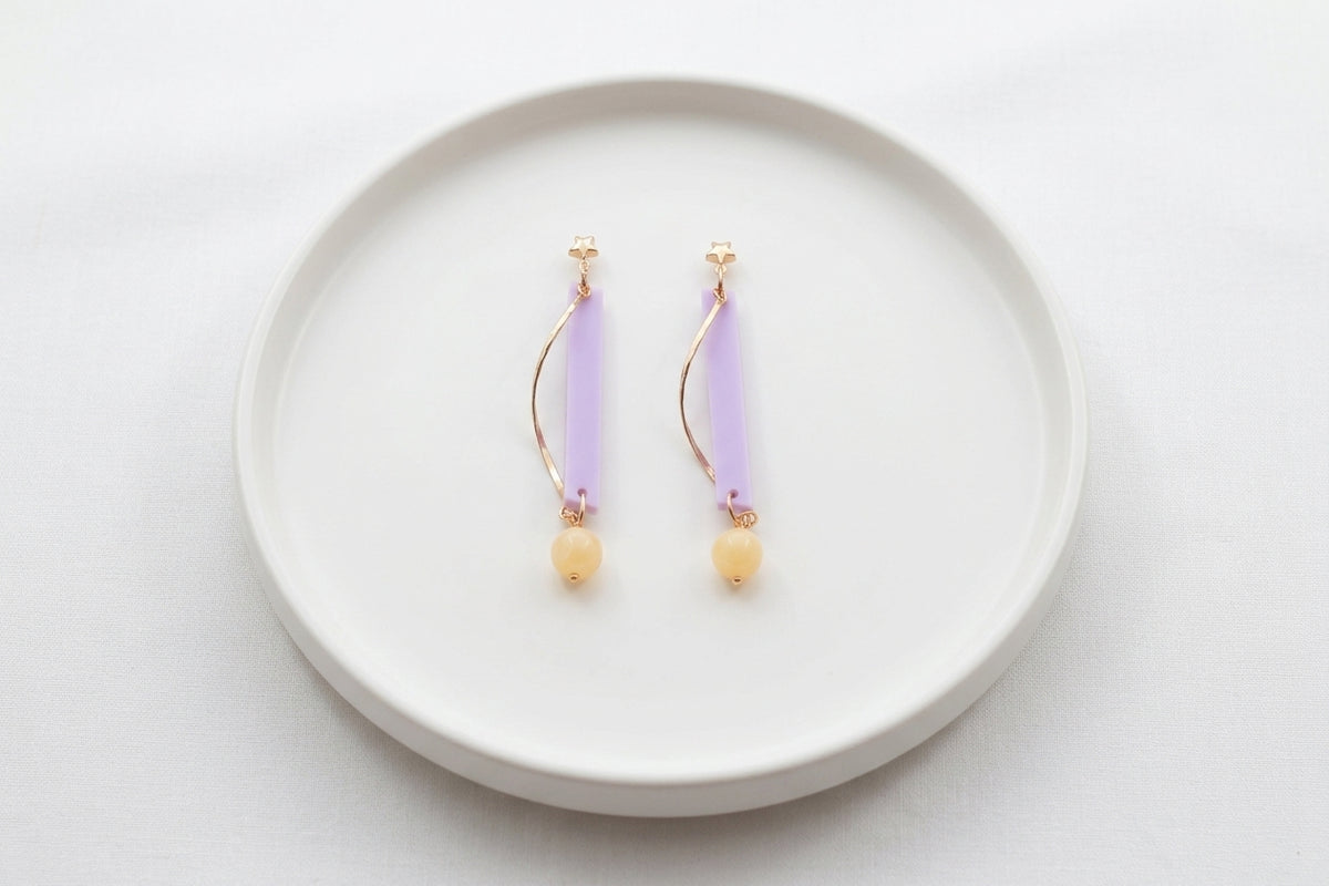 Purple Ina long rectangle acrylic earrings arranged on a white plate
