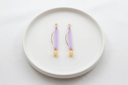 Purple Ina long rectangle acrylic earrings arranged on a white plate