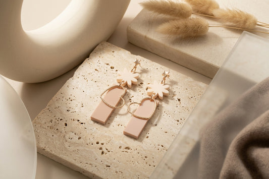 Beige Ines floral heart dangle earrings in a styled product setting
