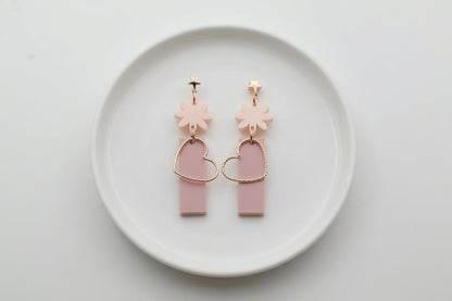 Beige Ines floral heart dangle earrings arranged on a white plate