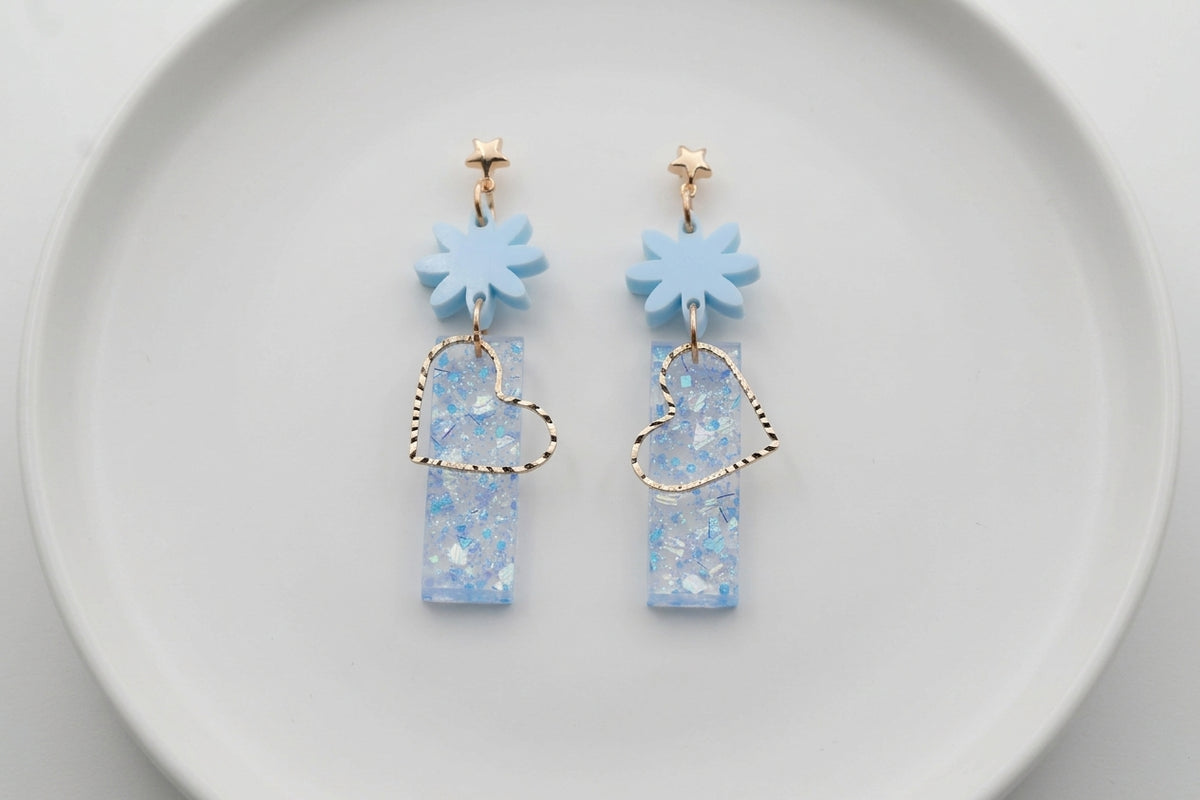 Blue Ines floral heart dangle earrings arranged on a white plate