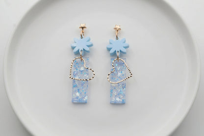 Blue Ines floral heart dangle earrings arranged on a white plate