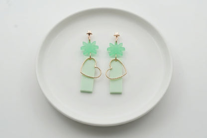 Green Ines floral heart dangle earrings arranged on a white plate
