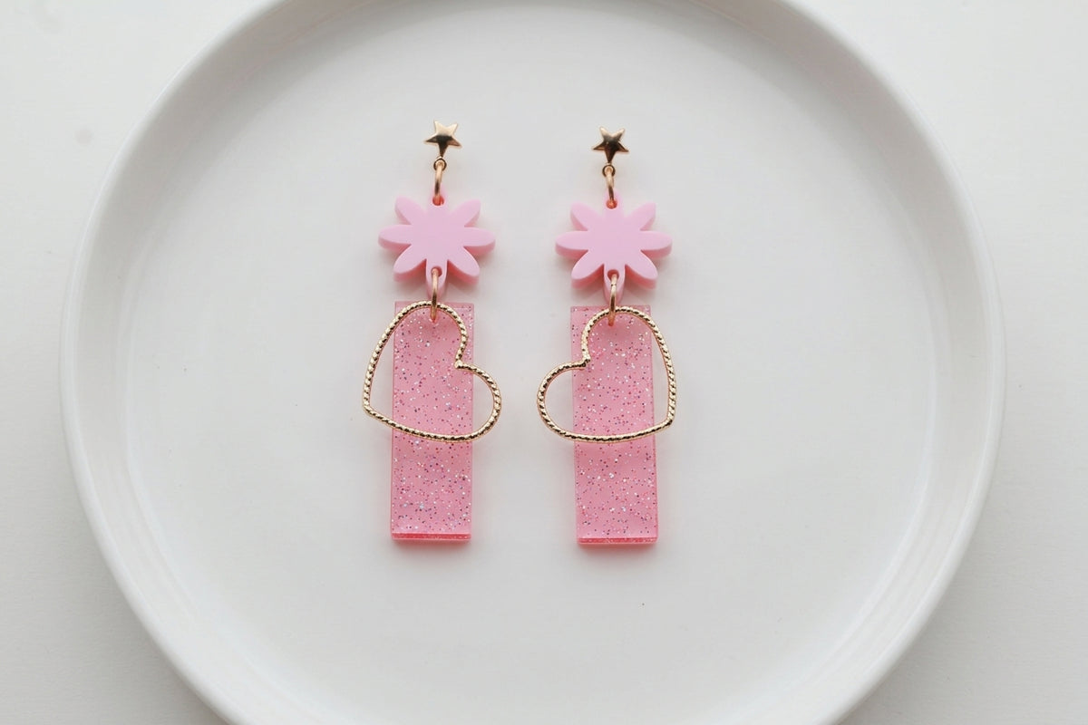 Pink Ines floral heart dangle earrings arranged on a white plate